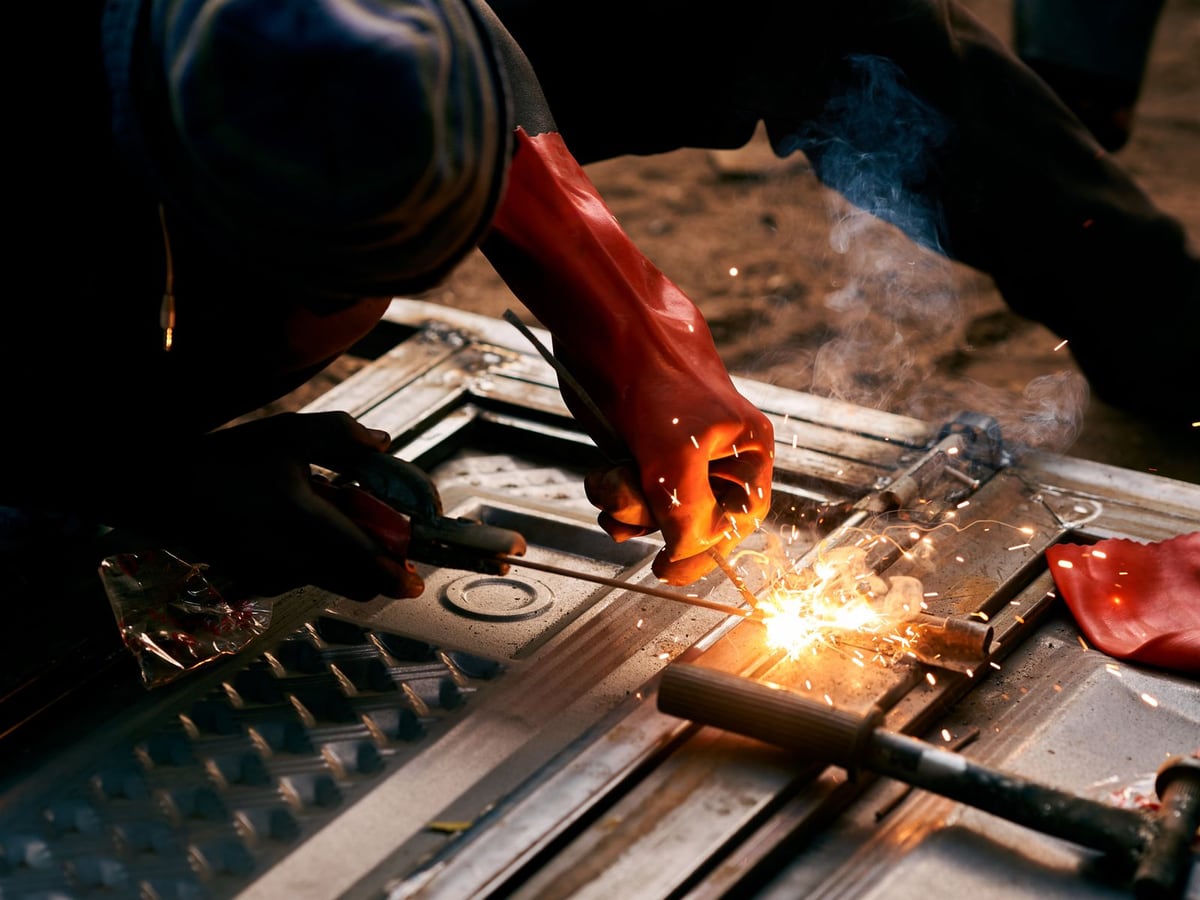 A cutting torch burning along steel stock clamped on a workbench &mdash; representative imagery, not a specific Late Night Fabrication job