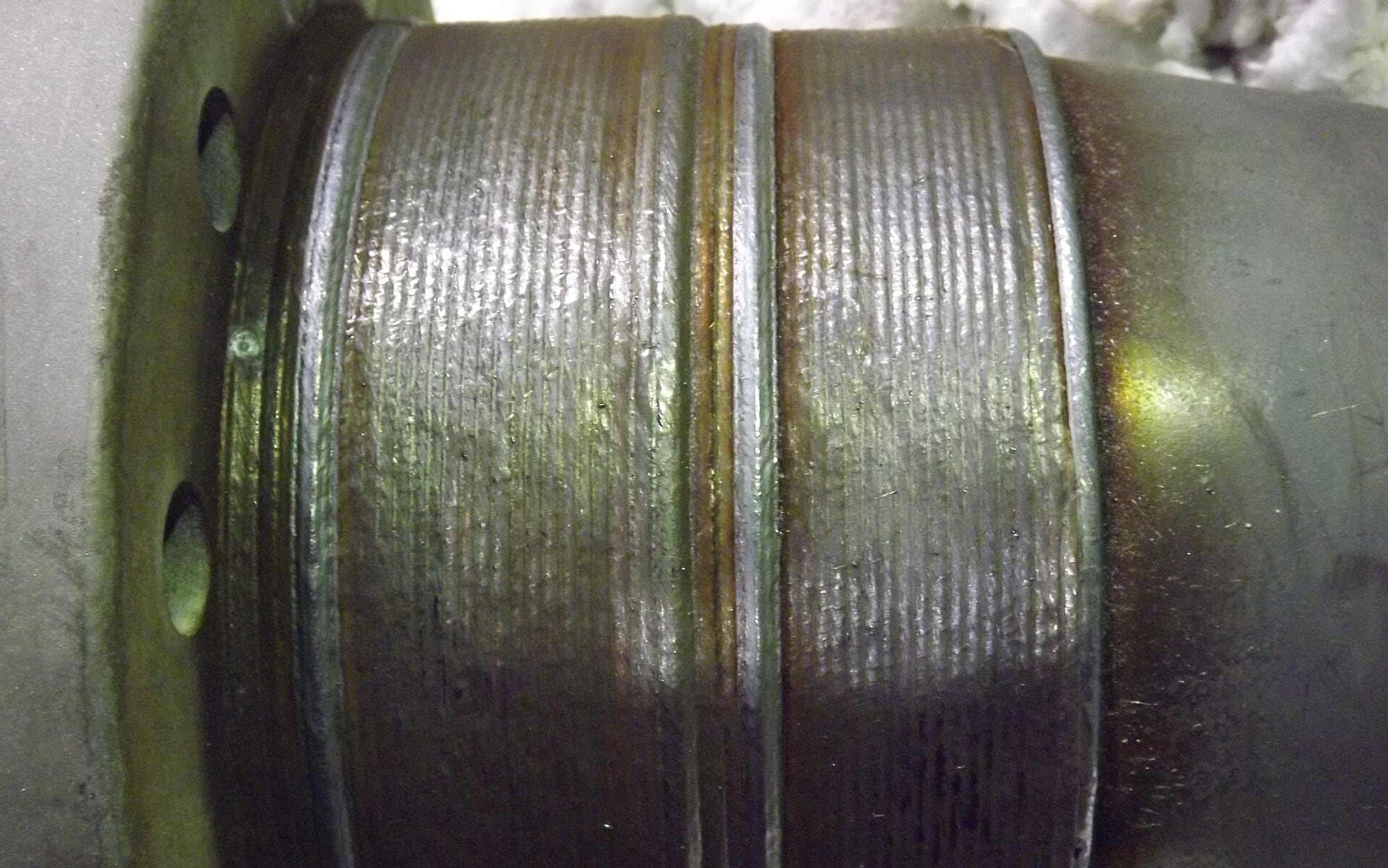 A macro photograph of stacked weld beads running around a welded steel pipe joint &mdash; representative imagery, not a specific Late Night Fabrication job